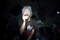 a man with blue hair singing into a microphone